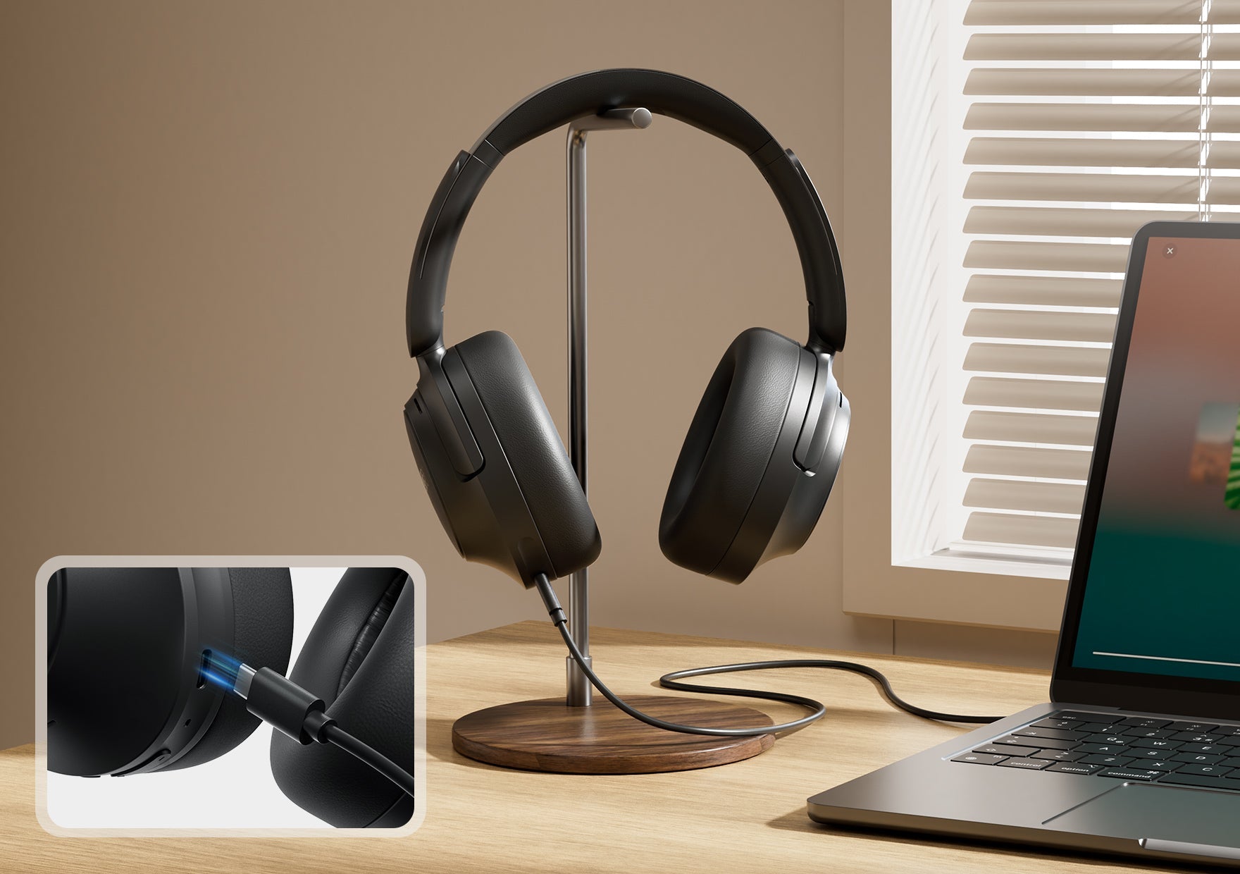 Schwarze Over-Ear-Kopfhörer mit Kabel auf Holzständer neben Laptop am Fenster.