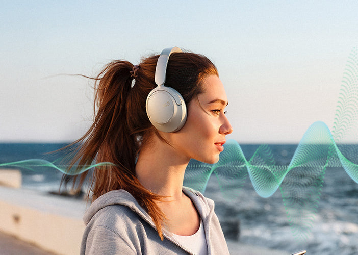 Frau mit kabellosen Kopfhörern am Meer, Musik hören