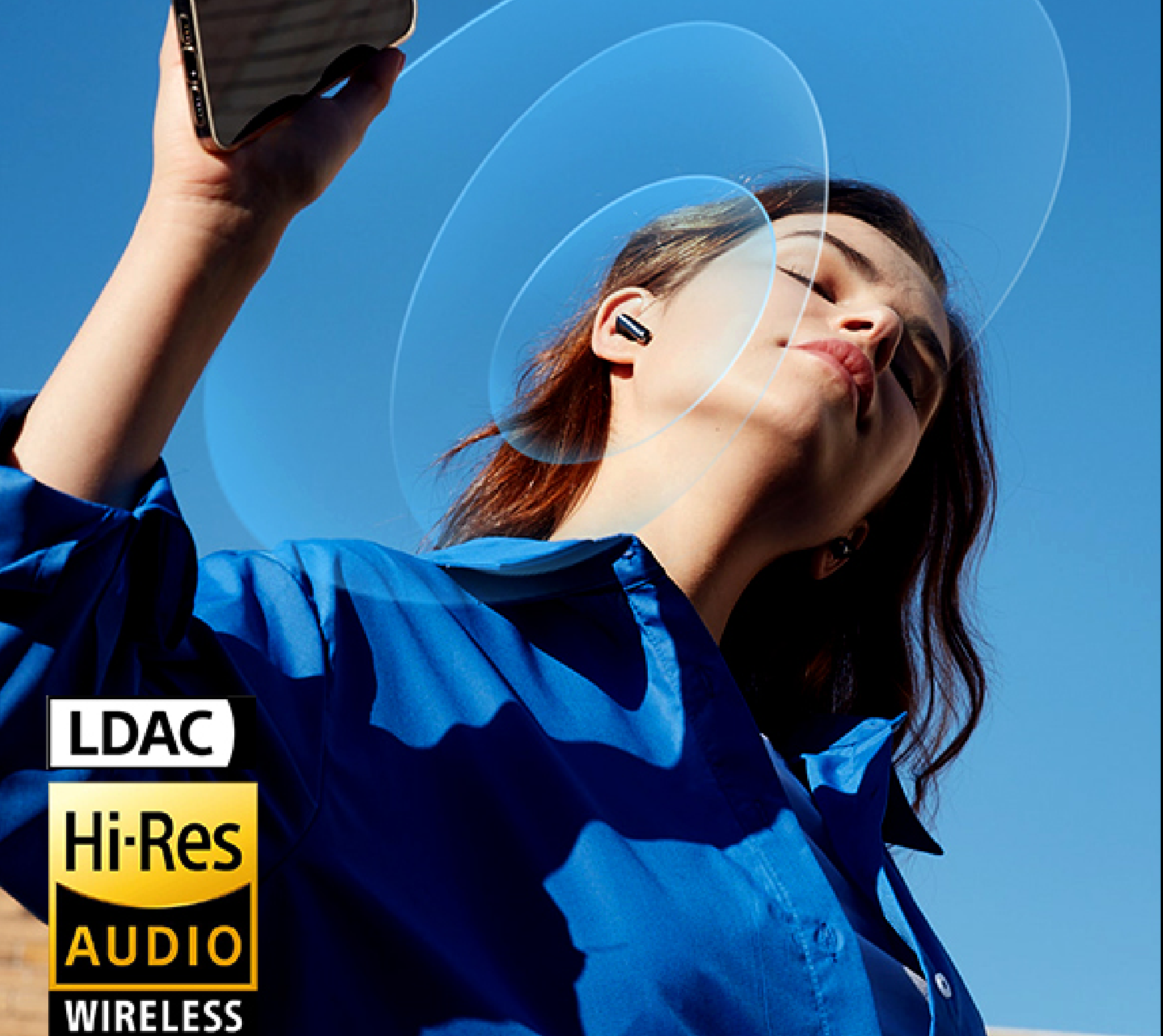 Frau mit kabellosen Hi-Res Audio Ohrhörern unter blauem Himmel, genießt Musik via LDAC Wireless Technologie.