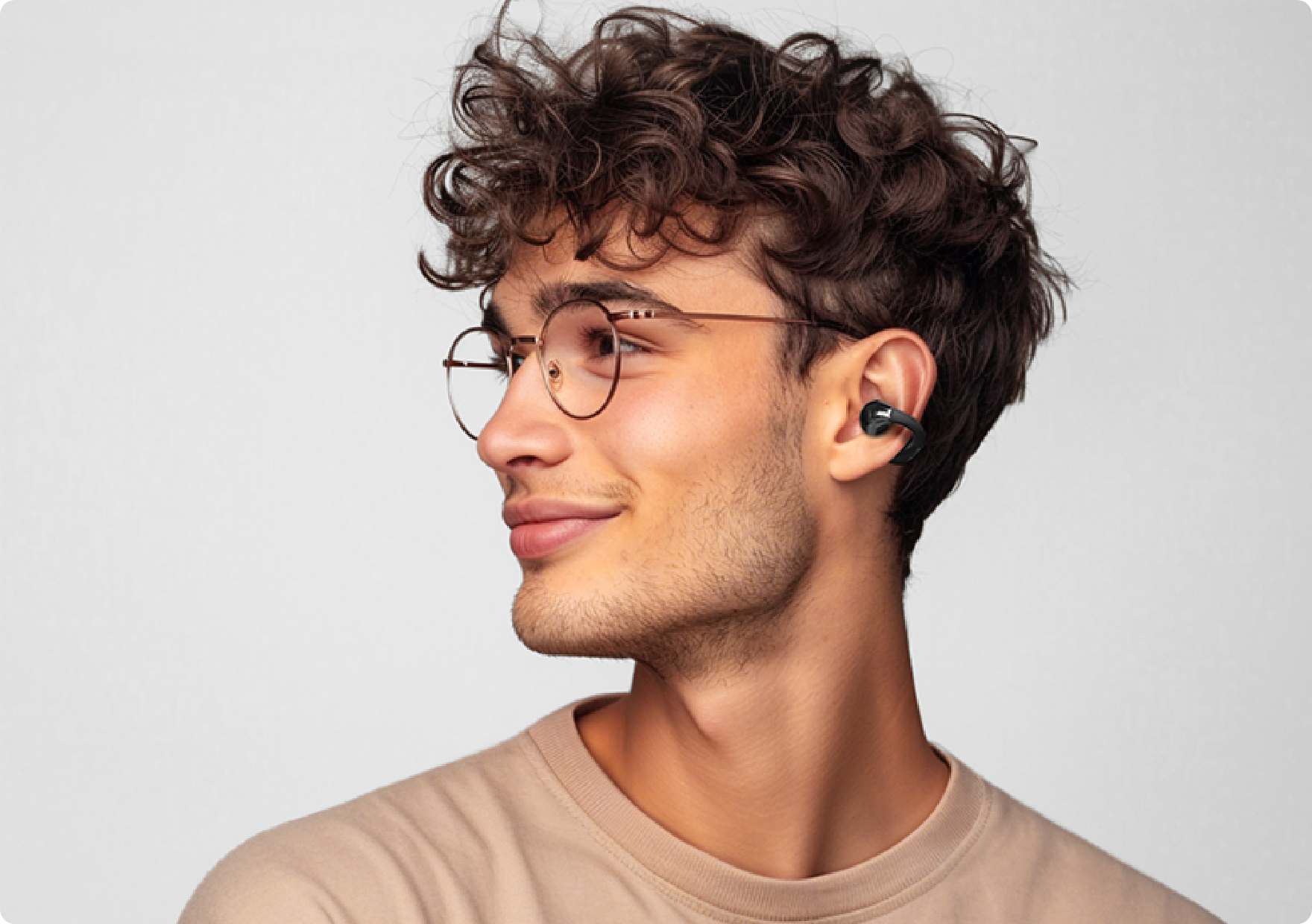 Junge Mann mit Brille und kabellosen Ohrhörern im Profil.