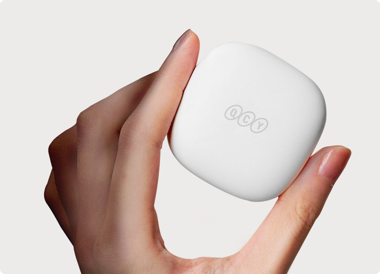 Weiße QCY-Ohrhörer-Box in der Hand, minimalistisches Design mit Logo, ideal für drahtlose Kopfhörer.
